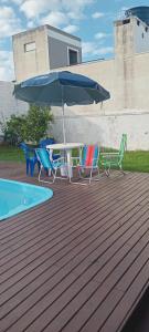 a patio with a table and chairs and an umbrella at QUARTO AZUL com cozinha e piscina só sua in Capão da Canoa