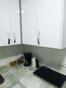 a kitchen with white cabinets and a coffee maker on a counter at La Joie Al Jadid in Nador +26 photos