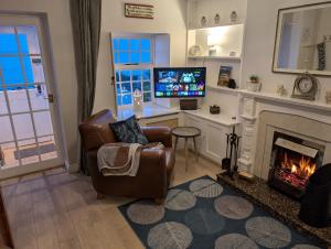 a living room with a fireplace and a chair at Widows Row Cottage in Newcastle