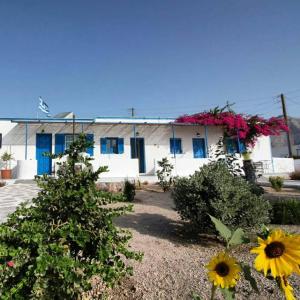 a house with blue windows and flowers in a yard at Glaros Beach in Perivolos