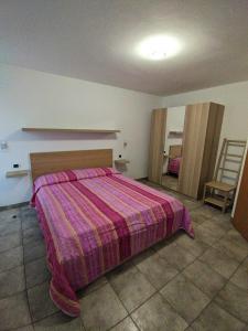 a bedroom with a large bed with a purple blanket at Cà da Nello in Pellizzano