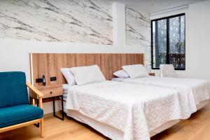 a bedroom with two beds and a blue chair at Hotel Santiago de Compostella Suites in Cuenca +42 photos