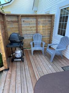 two chairs and a grill on a wooden deck at The Laurel Leaf at Annes Windy Poplars in Cavendish