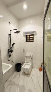 a white bathroom with a toilet and a bath tub at ComfortHomes in Ahor +23 photos