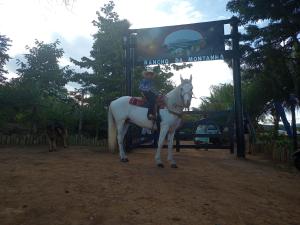 a person sitting on a white horse in front of a sign at Rancho da Montanha Chalé Lua in Resplendor