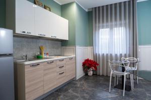 eine Küche mit weißen Schränken, einem Tisch und Stühlen in der Unterkunft Kora Rooms in Telese