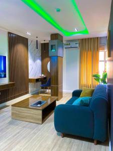 a living room with a blue couch and a tv at SUITE De PARIS in Abuja