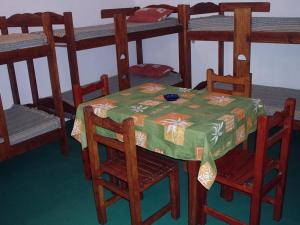 a room with a table and chairs and bunk beds at Hostal Sur in Villa Gesell