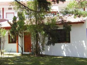 a white house with a tree in front of it at Hostal Sur in Villa Gesell