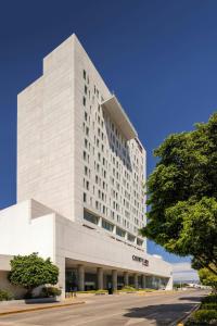 a large white building with a tree in front of it at Courtyard by Marriott Leon at The Poliforum in León