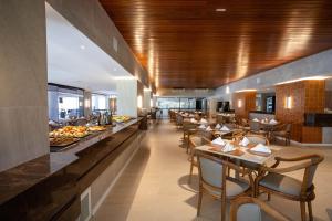 a restaurant with wooden ceilings and tables and chairs at Maceió Atlantic Suites in Maceió