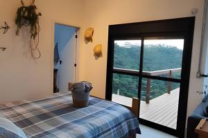 a room with a bed and a large window at Cabana do Café - Olivais Santa Clara in Cambuí