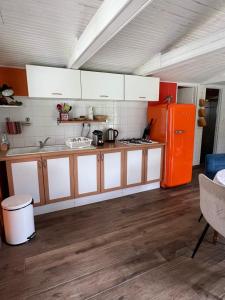 a kitchen with white cabinets and an orange refrigerator at chalet atypique, Ile chambod in Echallon