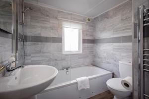 a bathroom with a tub and a sink and a toilet at Tranquil Lodge with river views in Hambleton +10 photos