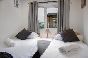 two beds in a room with a window at Tranquil Lodge with river views in Hambleton