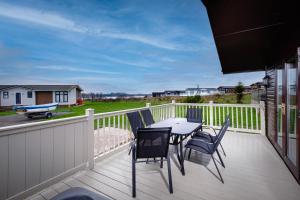 a patio with a table and chairs on a deck at Tranquil Lodge with river views in Hambleton