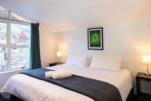 a bedroom with a large white bed with a window at Haka House Queenstown in Queenstown