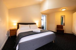 a bedroom with a large bed and a chair at Haka House Queenstown in Queenstown +21 photos