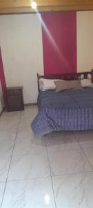 a bedroom with a bed and a purple wall at casita de campo in Chillán
