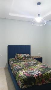 a bedroom with a bed with a blue headboard and a lamp at Luxury Mountain View Apartment in the City Center Free Private Parking & WiFi in Tétouan