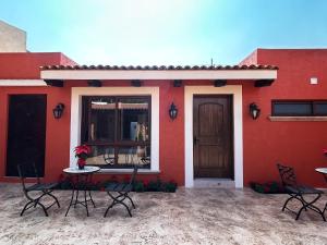 a red house with chairs and a table in front of it at Hacienda Casa Grande, suite esmeralda in Guadalajara