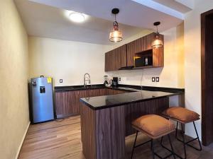 a kitchen with a blue refrigerator and two bar stools at Hacienda Casa Grande, suite esmeralda in Guadalajara