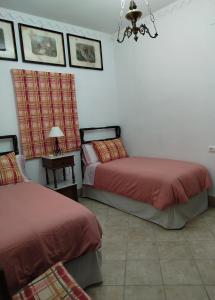 a bedroom with two beds and a table with a lamp at Casa Rural del Guadalora in Hornachuelos +14 photos