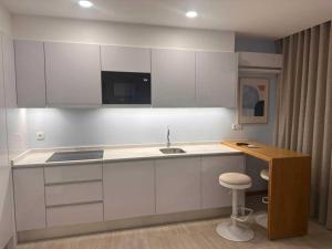 a kitchen with white cabinets and a sink and a stool at Hotel Buganvília in Funchal