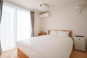 a bedroom with a large white bed and a window at Fujiyasan in Fujikawaguchiko