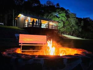 a fire pit with a bench in front of a building at Chalé Pôr do Sol in Cunha