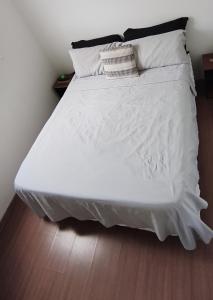 a large white bed with white sheets and pillows at Doce Encanto in Uberaba