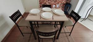 a wooden table with four chairs and plates on it at Doce Encanto in Uberaba