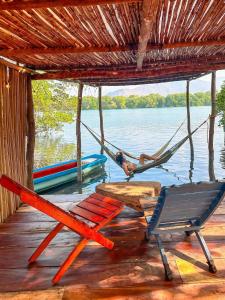 a hammock and a chair on a dock with a boat at Entremares in Boca del cielo
