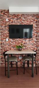 a table in front of a brick wall with a tv at Doce Encanto in Uberaba