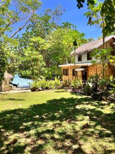 a house with a grass yard next to the ocean at Beachfront on Aore Island Private Island Stay in Aimbuei Bay
