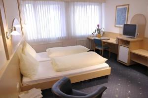 a room with two beds and a desk with a computer at Hotel Hecher in Wolfsberg