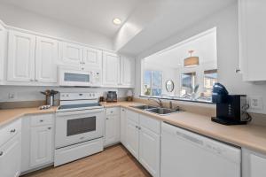 a kitchen with white cabinets and a sink and a window at Doc's Folly in Gulf Shores +29 photos