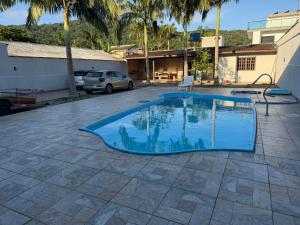 a blue swimming pool in a yard with a house at Sobrado prainha caioba in Guaratuba