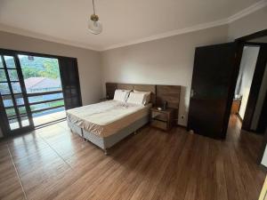 a bedroom with a bed and a wooden floor at Sobrado prainha caioba in Guaratuba
