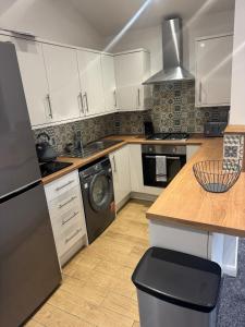 a kitchen with white cabinets and a washing machine at Cozy bungalow in Standish