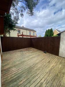 a wooden deck in a backyard with a fence at Cozy bungalow in Standish