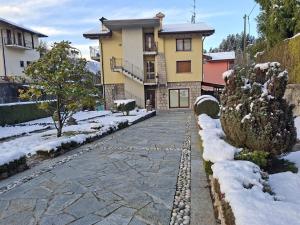a house with a stone walkway in the snow at La cà de Clüsu in Clusone
