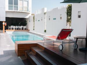 a red chair sitting on a deck next to a swimming pool at Metria Hotel in León