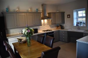 a kitchen with a wooden table with a vase of flowers on it at Sally Gardens Cottage in Downpatrick