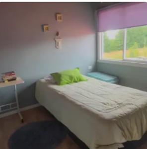a small bedroom with a bed and a window at Casa Arrayán con vista al volcan in Frutillar
