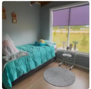 a bedroom with a bed and a desk and a window at Casa Arrayán con vista al volcan in Frutillar