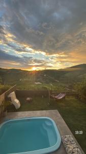 a swimming pool on a patio with a sunset in the background at Loft das Maritacas - Conservatória in Valença