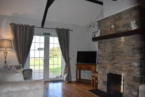 a living room with a stone fireplace and a television at Sally Gardens Cottage in Downpatrick