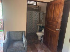 a bathroom with a toilet and a chair next to a door at Jardines del Golfo in Lepanto +34 photos