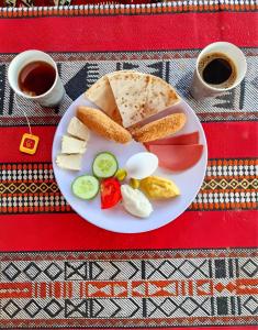a plate of food with eggs and bread and two cups of coffee at Moonlight Luxury Bubble Camp & Jeep Tours in Wadi Rum